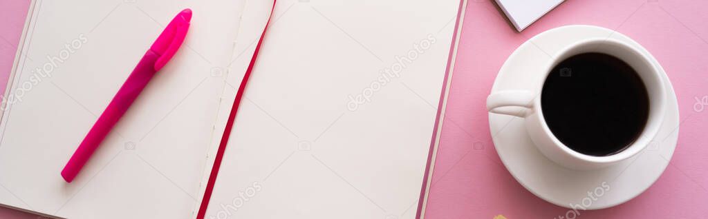top view of pen on open notebook near cup of coffee and notebook on pink, banner