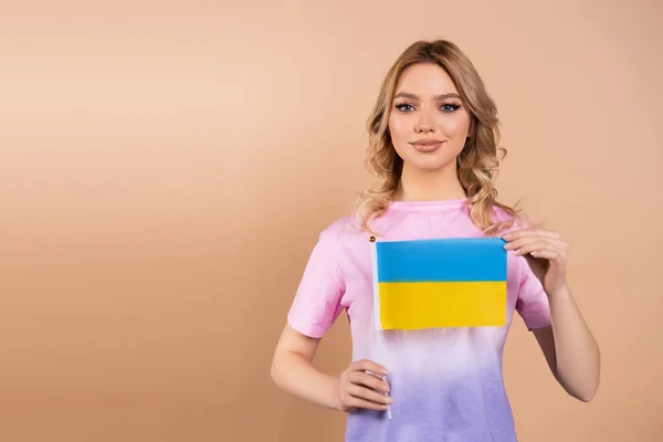 Smiling Woman Small Ukrainian Flag Looking Camera Isolated Beige — Zdjęcie stockowe