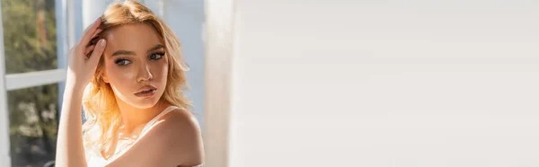 Sensual Young Woman Touching Wavy Hair Blurred Window White Copy — Zdjęcie stockowe