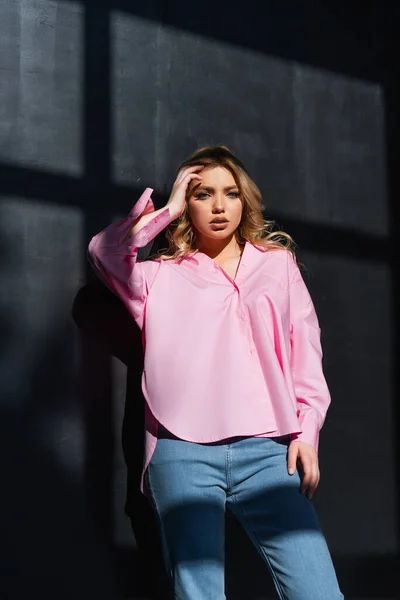 Young Woman Pink Shirt Jeans Looking Camera Black Wall Shadows — Foto de Stock