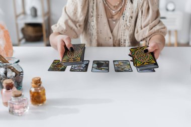 KYIV, UKRAINE - FEBRUARY 23, 2022: Cropped view of fortune teller holding tarot cards during divination at home 