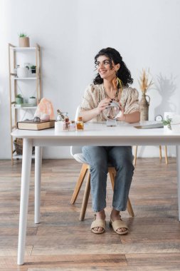 Positive gypsy medium touching orb near book and magic crystals on table 