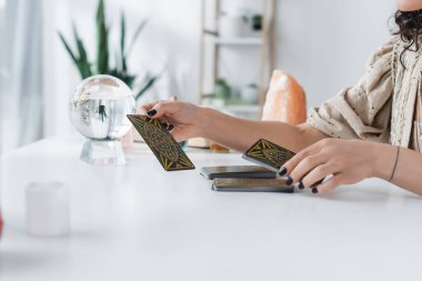 KYIV, UKRAINE - FEBRUARY 23, 2022: Cropped view of medium holding tarot cards at home 