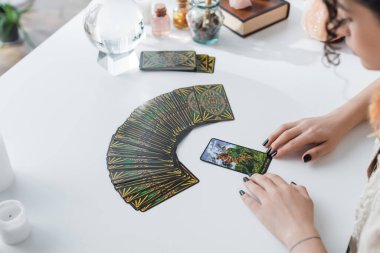 KYIV, UKRAINE - FEBRUARY 23, 2022: High angle view of blurred gypsy fortune teller looking at tarot cards 