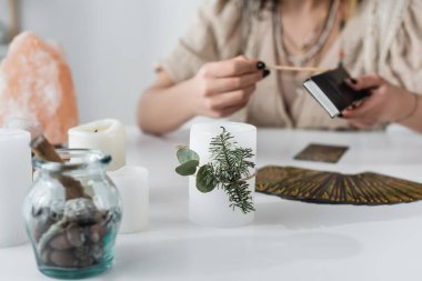 Cropped view of candles near blurred medium and tarot cards on table  clipart