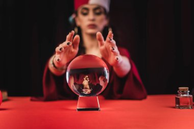 Magic orb near blurred fortune teller isolated on black 