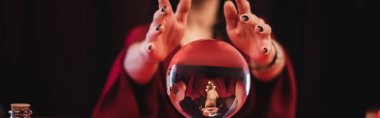 Cropped view of blurred soothsayer and magic orb isolated on black, banner  clipart