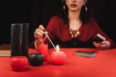 Kırpılmış görüntü bulanık yanan mum ve izole edilmiş tarot kartları. 