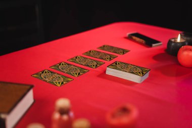 KYIV, UKRAINE - FEBRUARY 23, 2022: Tarot near candles and blurred book on table isolated on black 