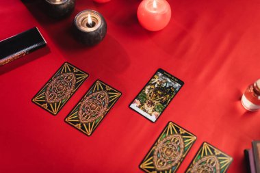 KYIV, UKRAINE - FEBRUARY 23, 2022: Top view of tarot cards near burning candles on table 