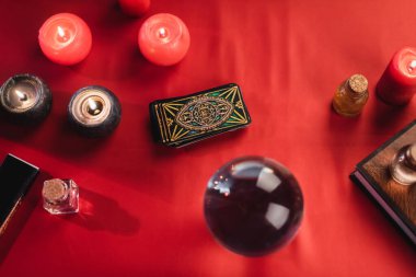 KYIV, UKRAINE - FEBRUARY 23, 2022: Top view of tarot cards near burning candles and book on table 