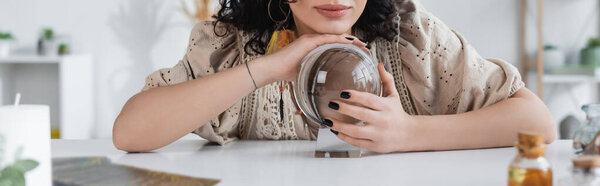 Cropped view of soothsayer touching glass orb at home, banner 