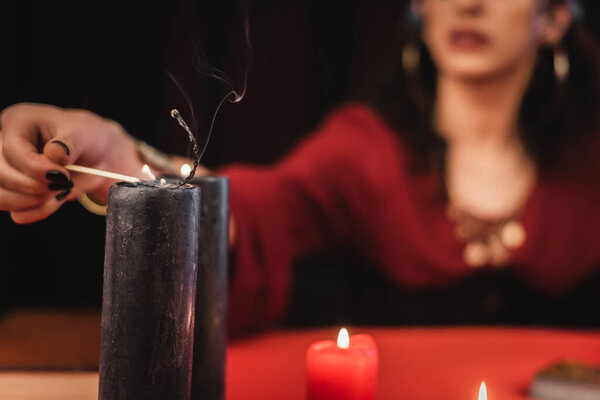 Cropped view of blurred medium burning candle isolated on black 
