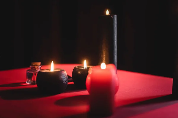 Burning candles and jar on table isolated on black
