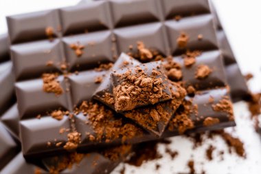 Top view of dry cocoa on blurred chocolate bars on white background 