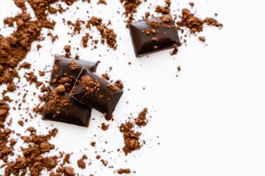 Beyaz arka planda çikolata parçalarının üzerindeki bulanık kakao tozunun üst görünümü 