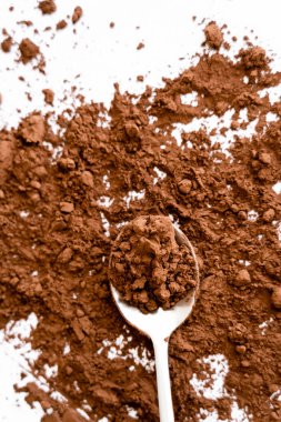 Top view of natural cocoa powder on spoon on white background  clipart