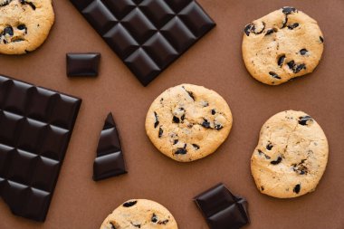 Top view of cookies and dark chocolate on brown background 