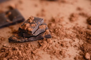 Bulanık kahverengi arka planda doğal kakao tozu ve çikolatanın yakın görüntüsü 