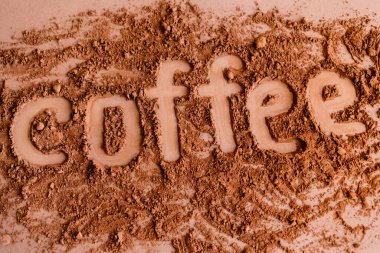 Top view of coffee lettering in cocoa on brown background  clipart