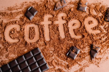 Kahverengi arka planda kakaolu kahve harflerinin ve çikolatanın üst görüntüsü 