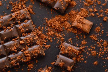 Top view of natural cocoa powder on chocolate on black surface 