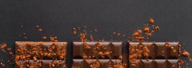 Top view of natural cocoa powder on dark chocolate on black background, banner 