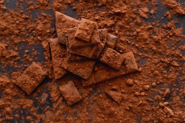 Kuru kakaonun siyah arkaplandaki çikolata parçalarının üst görüntüsü 