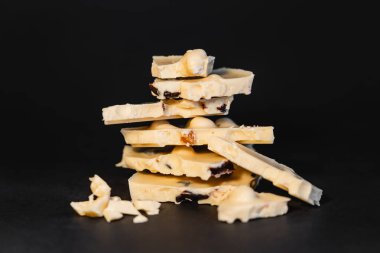 Close up view of pieces of white chocolate with nuts on black background 
