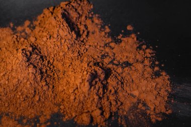Top view of natural brown cocoa powder on black background  clipart