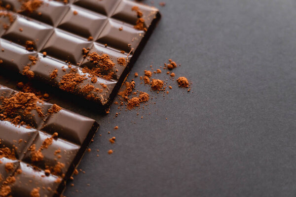 Close up view of natural cocoa on chocolate on black background with copy space