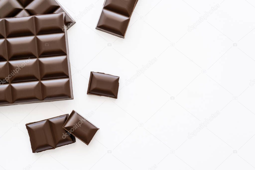 Top view of pieces and bars of chocolate on white background 