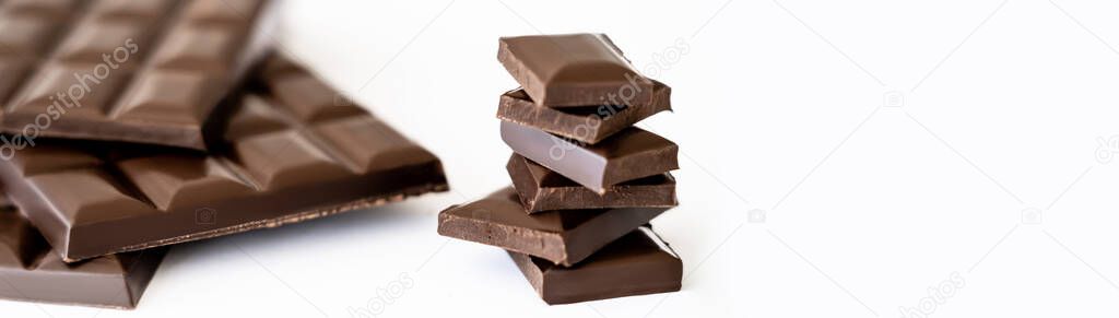 Close up view of chocolate pieces near blurred bars on white background, banner 
