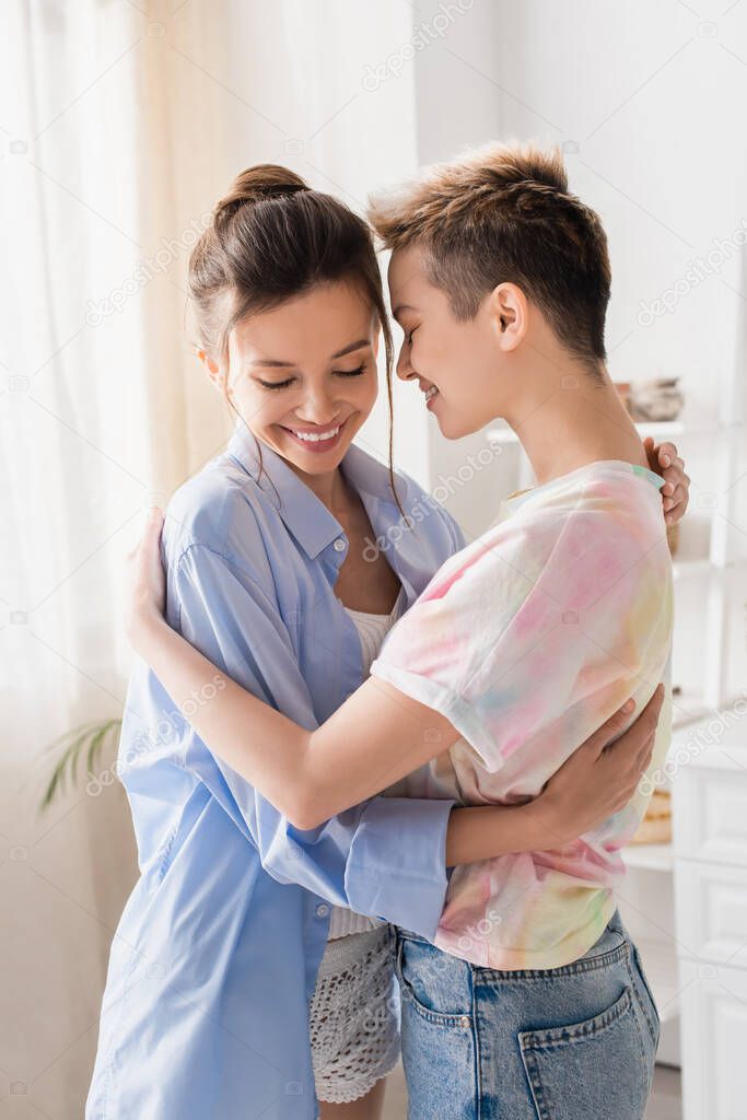 cheerful young pangender people embracing in kitchen