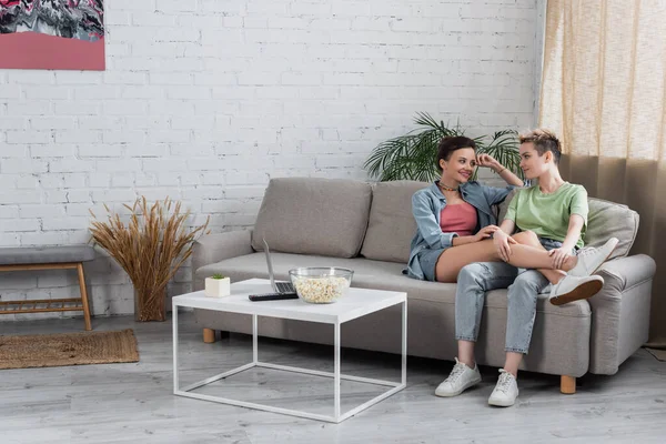 Smiling Bigender Couple Talking Couch Living Room Laptop Popcorn Coffee — Stock Fotó