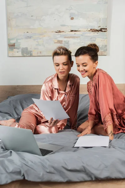 Young Pansexual Couple Looking Document While Working Laptop Bed — Stock Fotó