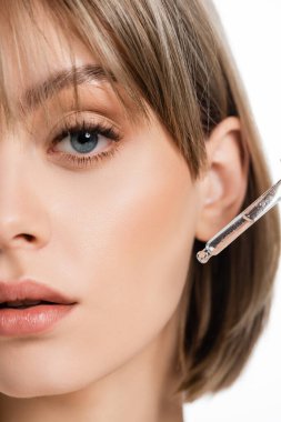 Beyaz üzerine izole edilmiş pipeti olan serumu uygulayan genç bir kadın.