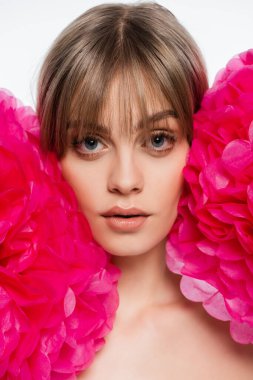 young woman with blue eyes near bright pink decorative flowers isolated on white