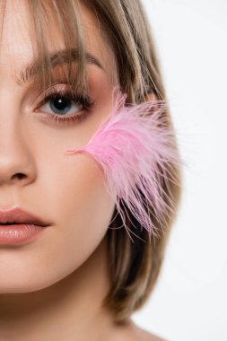 cropped view of sensual young woman with pink feather on face isolated on white clipart