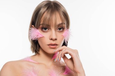 sensual young woman with decorative elements on face and body and pink feathers on cheeks isolated on white
