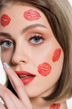 close up of young woman with red kiss prints on cheeks and body isolated on white