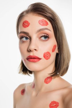 young woman with red kiss prints on face looking away isolated on white