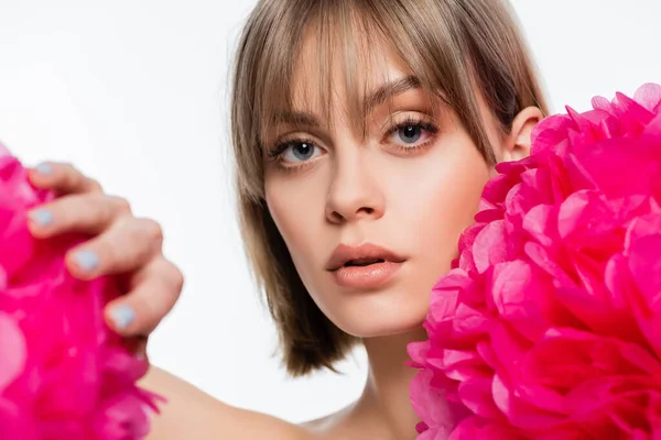 blonde young woman with bangs near bright pink flowers isolated on white