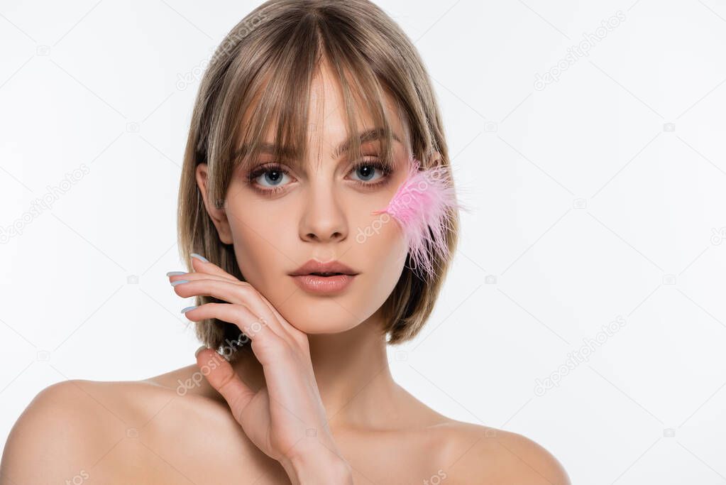 sensual young woman with bare shoulders and pink feather on face isolated on white