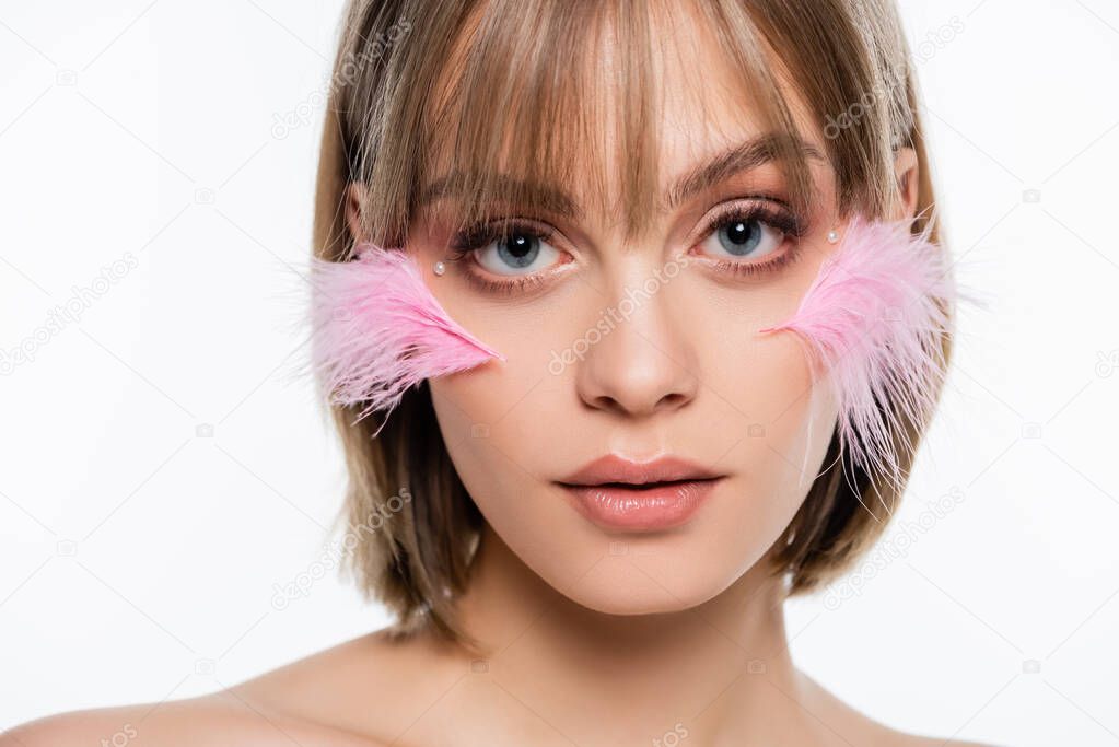 young woman with decorative elements in makeup and pink feathers on cheeks isolated on white