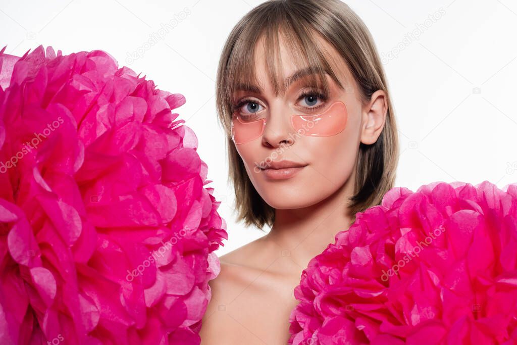 young woman with hydrogel eye patches near bright pink flowers isolated on white