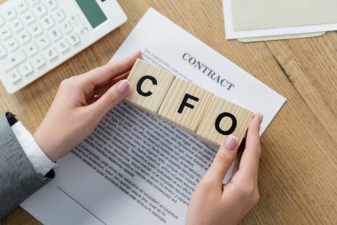 Üst düzey iş kadını elinde tahta küplerle Cfo harfleriyle kontrat ve hesap makinesi tutuyor. 