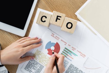Dijital tabletin yanında tablolar ve Cfo harfli küplerle çalışan finans müdürünün üst görüntüsü 