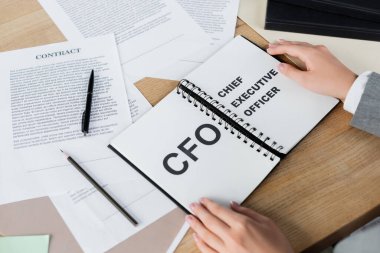 CFO ve üst düzey yönetici harfleriyle defter tutan bir kadın. 