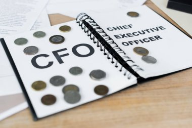 silver and golden coins on notebook with cfo and chief executive officer lettering  clipart